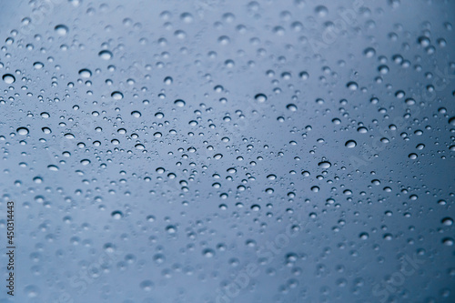 Close up of rain drops on window with blue gray background of dark sky