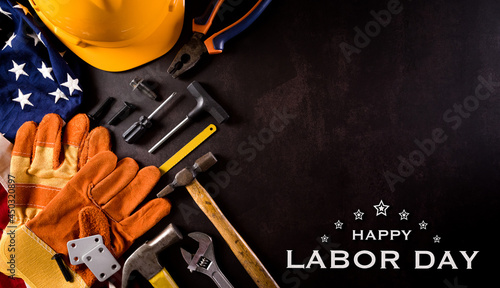Happy Labor day concept. American flag with different construction tools and the text on dark stone background. © Siam