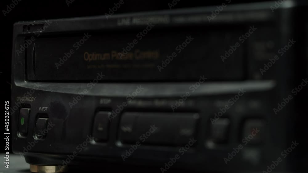 Taking video cassette into recorder. Using videotape. Old retro