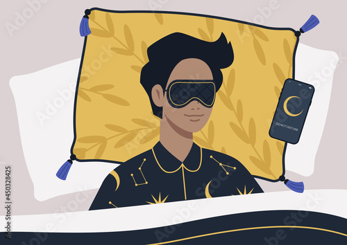 A young male character wearing a night mask and silk pajamas in bed, a mobile phone on silent mode next to them on a pillow