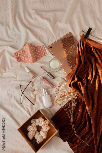 Fashion women's composition with beautiful stylish skirt, earrings and face mask fashion trend on white linen blanket. Flat lay, top view lifestyle concept.