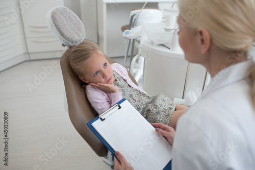 Small blonde girl having an appointment with the pediadontis photo