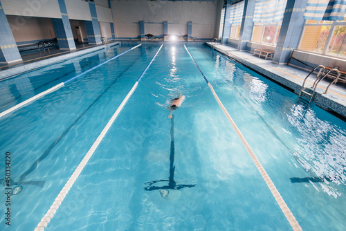 A young athlete trains and prepares for swimming competitions in the pool. Healthy lifestyle. © Andrii