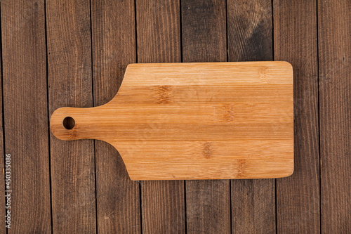 Top view on light brown wooden cutting board on a wooden background