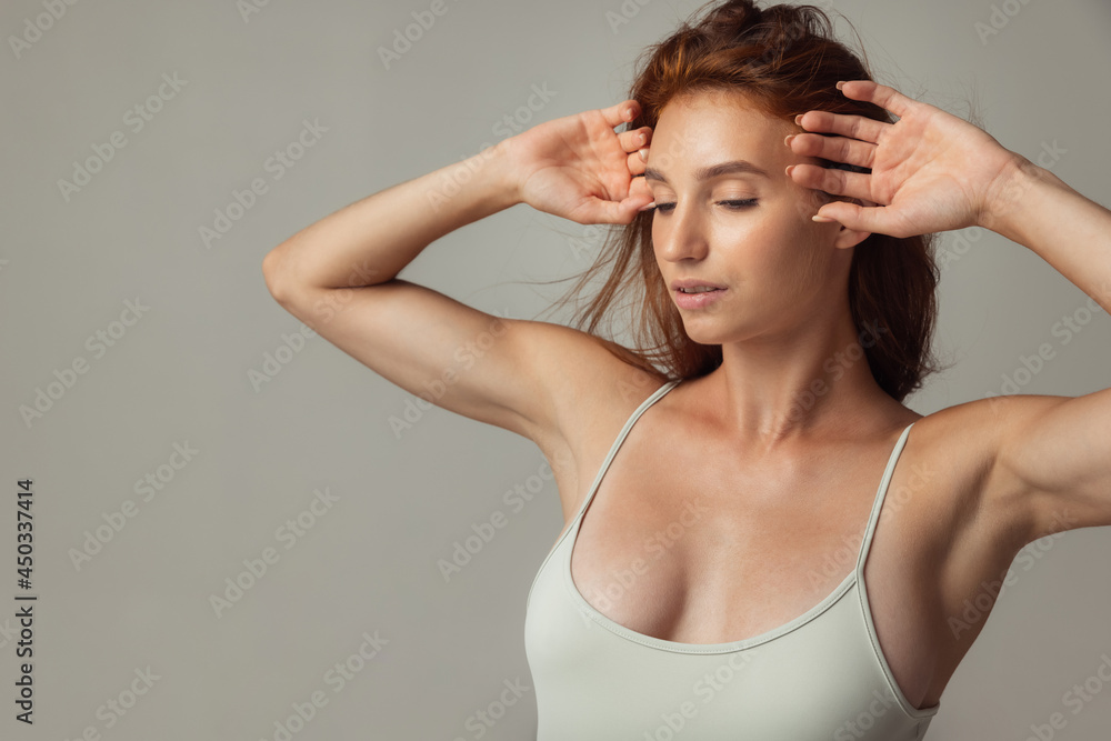 Close-up portrait of young beautiful red-headed woman without makeup isolated over gray studio background. Natural beauty concept.