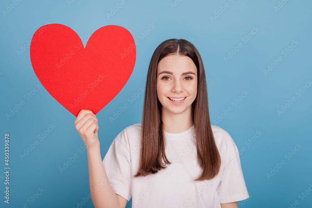 Portrait of affectionate cute lady demonstrate red heart paper postcard on blue background Portrait of affectionate cute lady demonstrate red heart paper postcard on blue background