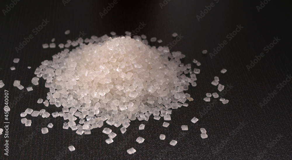 Sugar in glass bowl on wooden background.