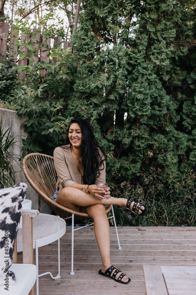 Naklejka premium Young adult filipino woman sitting outside relaxing on patio