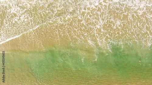 AERIAL. Top view of young pretty of woman floating in amazing clear waters, girl swimming at the ocean, wearing bikini, beautiful sea, foam yellow sand, view on ocean, relax and having fun on vacation