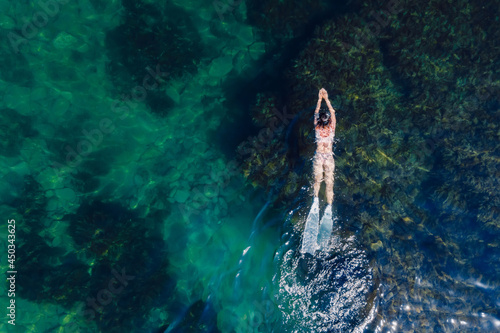 Free diver woman with freediving fins swimming in blue ocean. Aerial view