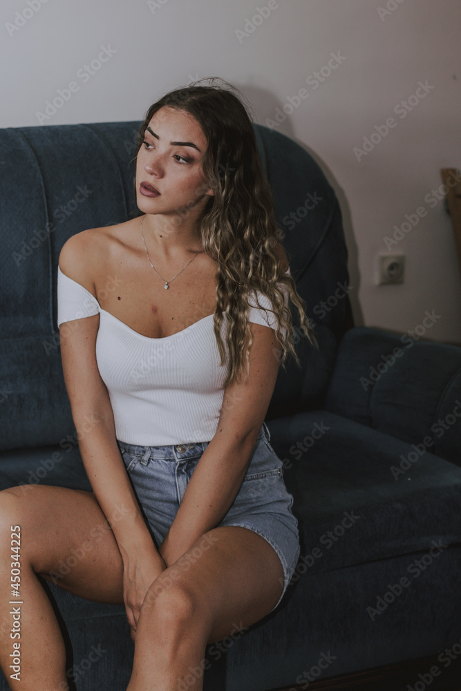 Obraz premium Indoor portrait of a young beautiful romantic woman .Head shot portrait young woman sitting on couch