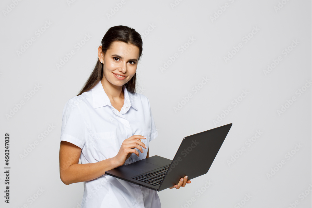 Portrait of a female laboratory assistant holding laptop.Young female doctor on a gray background. Portrait of a female laboratory assistant holding laptop.Young female doctor on a gray background.