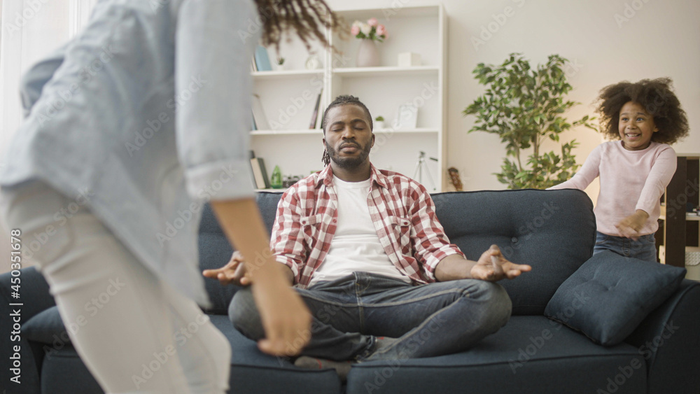 Obraz premium Black dad trying to keep calm while sitting in yoga pose, kids running around