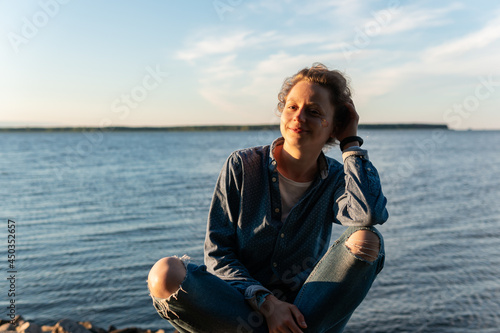 Happy woman sitting in front of sea on a warm sunny summer day