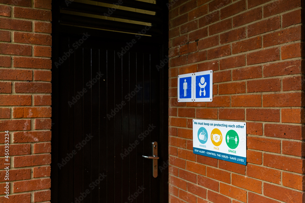 Obraz premium Covid-19 sign outside a public toilet informing the public of the current hands, face, space rules from the government to keep people safe and the virus from spreading