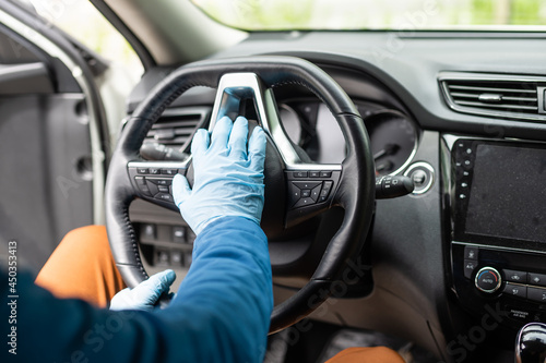 Covid-19 concept. Man drives in car, wears medical gloves, protects himself from bacteria and virus, holds car steering wheel. Coronavirus protection. Transport, quarantine and corona disease. © Angelov