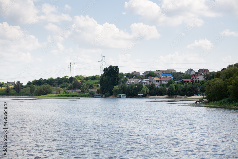 Fototapeta premium Reeds along banks of river with river houses docked on the opposite side reflecting in still waters. Weekend by the river. Fishing lake