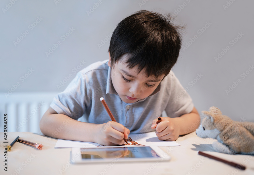 School Kid using colour pen drawing and painting on paper, A Boy using tablet for homework, Child colouring dog toys on paper, E-learning online education School Kid using colour pen drawing and painting on paper, A Boy using tablet for homework, Child colouring dog toys on paper, E-learning online education