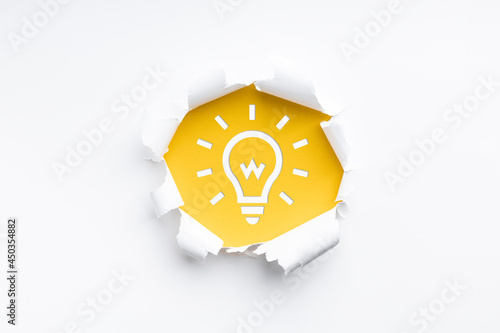 torn paper revealing a light bulb symbol #450354882