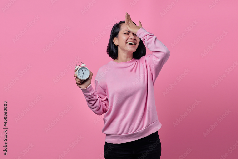 Fototapeta premium Shocked young woman holds white alarm clock in hand