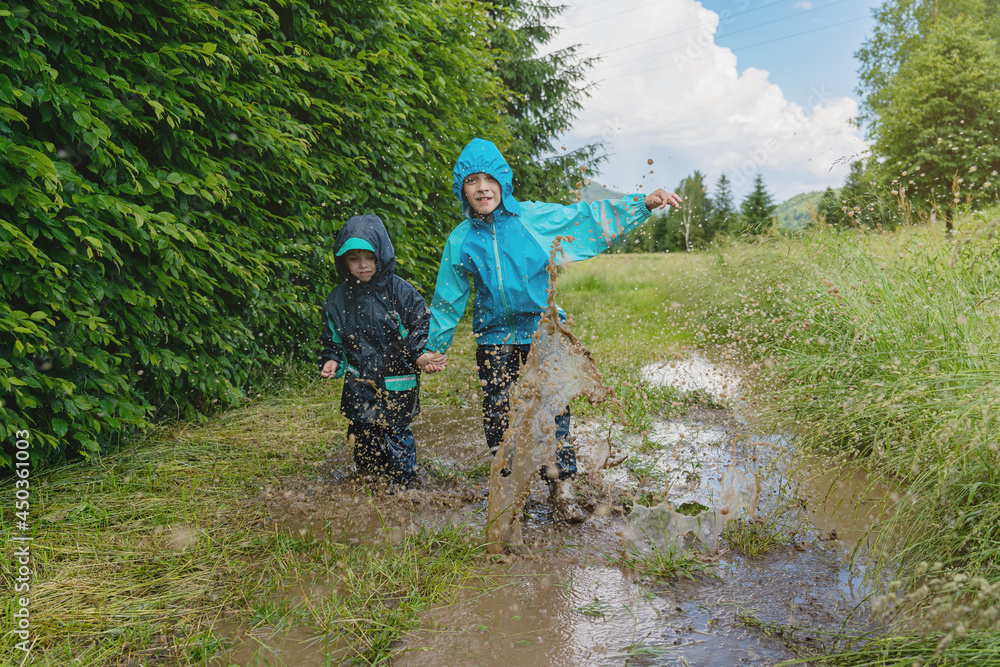 Children jump in a dirty puddle. Lots of splashes of water.