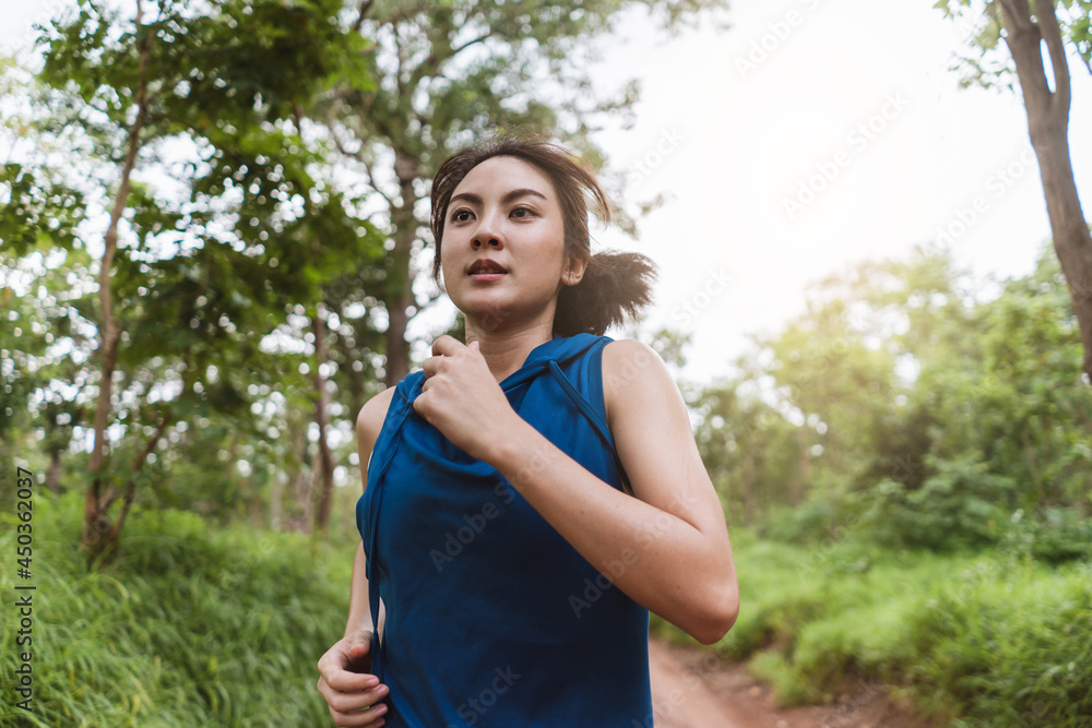 Active young Asian woman running at tropical forest trail. Portrait female runner trail running in the forest. Healthy lifestyle. Active young Asian woman running at tropical forest trail. Portrait female runner trail running in the forest. Healthy lifestyle.