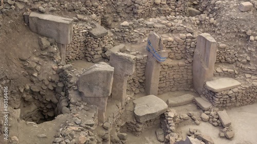 Gobeklitepe, Sanliurfa, Turkey - 15th of June 2021: 4K Zoom out remains of stone pillars and walls with animal reliefs
 photo