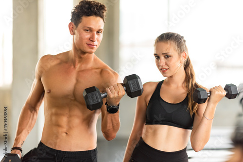 Personal trainer coach helping young woman exercising in the sport gym, training for active workout in fitness, body healthy sport lifestyle © chokniti