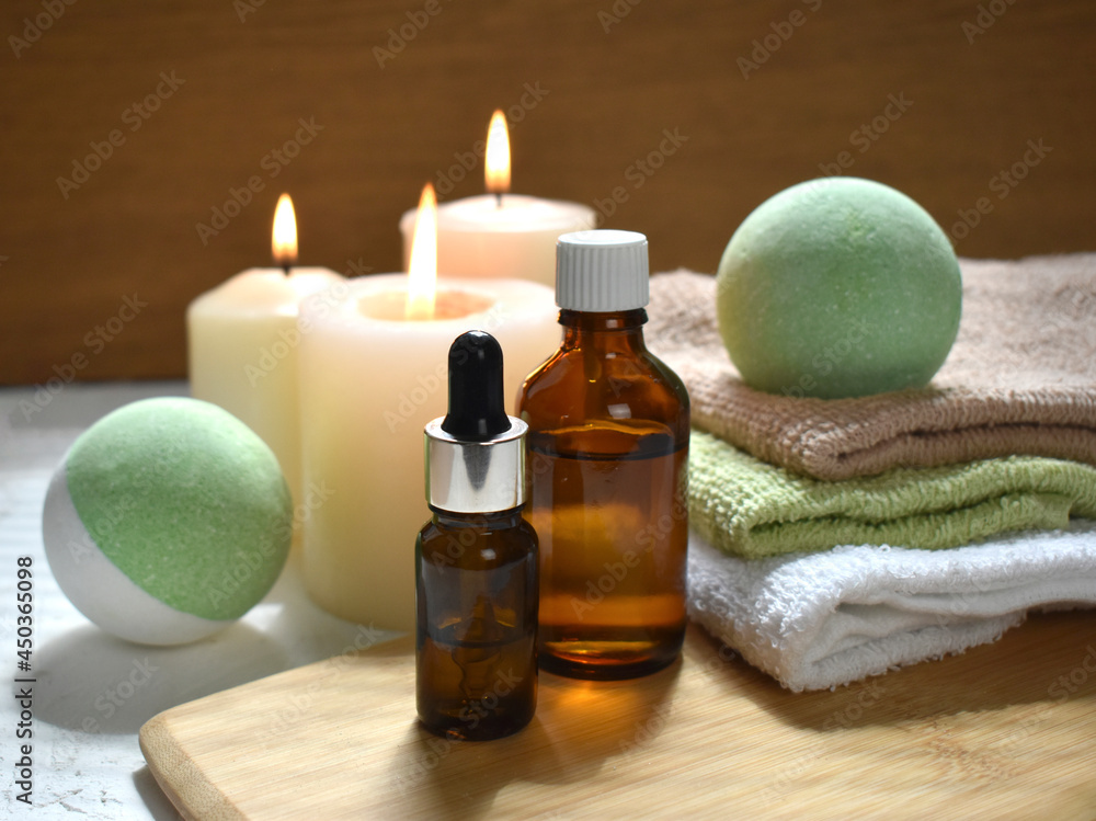 Spa aromatherapy still life with bath bombs, essential oil bottles and lit candles on wooden background. Natural cosmetic products treatment. Wellness. Massage. Trendy still life for resort, salon. Spa aromatherapy still life with bath bombs, essential oil bottles and lit candles on wooden background. Natural cosmetic products treatment. Wellness. Massage. Trendy still life for resort, salon.