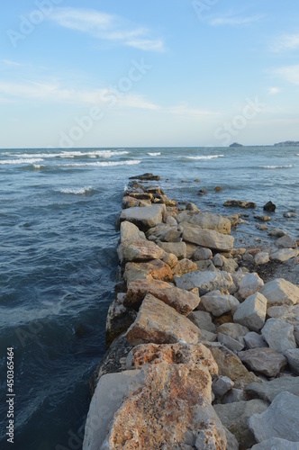 Rocky path into the mediterranean sea with Peñiscola's castle in the background and a blue perfect sky.