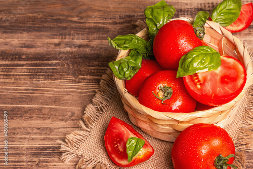 Ripe red tomatoes with fresh basil in a wicker basket