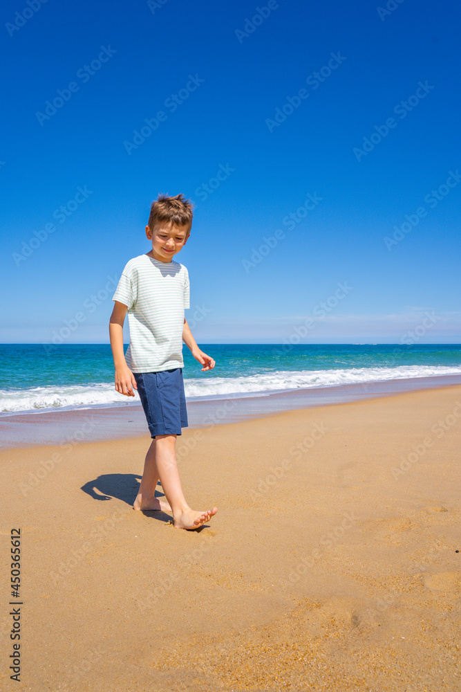 Happy boy walking and playing on the summer beach. Young teenager relax and having fun in summer holiday vacation travel. Happy boy walking and playing on the summer beach. Young teenager relax and having fun in summer holiday vacation travel.