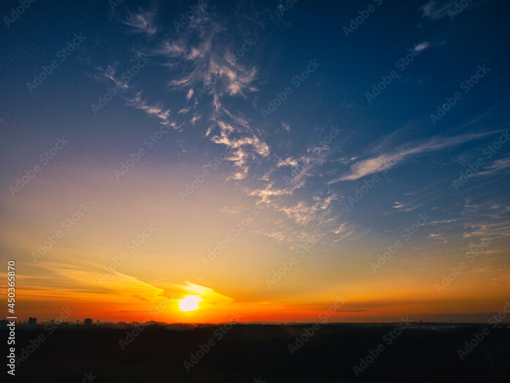 sunrise over a field in Germany with forest and cityline in background