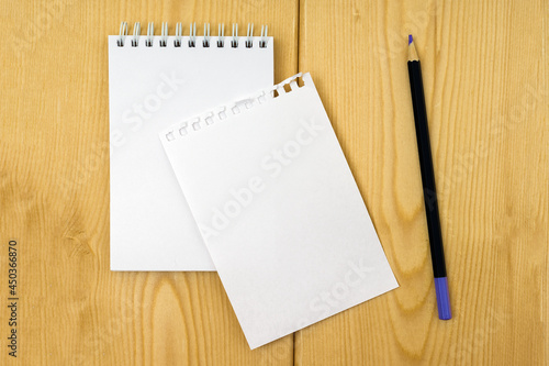 blank notepad with torn off white sheet and pencil on wooden background