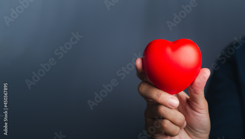 Hand of holding red heart shape against a gray background. Close-up photo. Sign of love, healthcare, valentine's day, world heart day concept