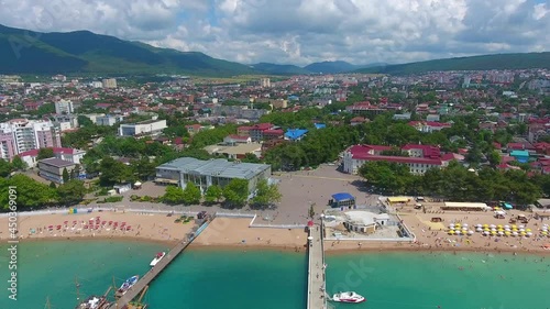 Aerial view of seaport and embankment in resort of Gelendzhik, ships, yachts and sailboats on the Black Sea coast and part of panorama of city, caucasus mountains Morkhort ridge