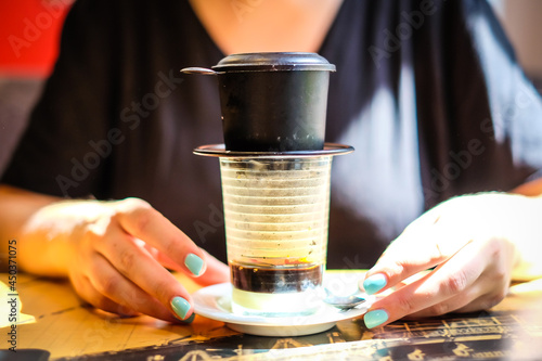 Woman holds cup of Vietnamese coffee. Defocused