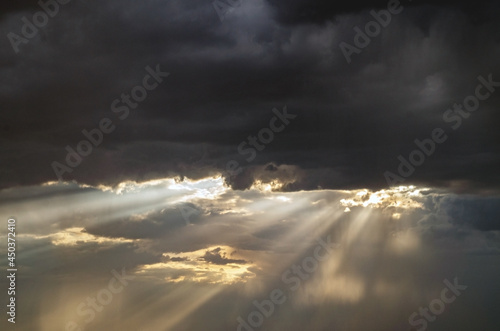 A ray of light through the clouds. Rays of light breaking through dark clouds, a dramatic sky with clouds.Bright sun during the rain. © Roman