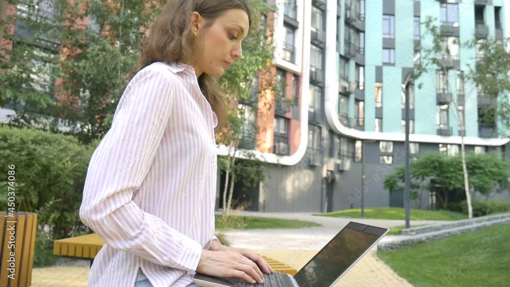 Young woman typing on keyboard of laptop, businesswoman using digital tablet outside on modern building background, account manager working outdoor, remote job Young woman typing on keyboard of laptop, businesswoman using digital tablet outside on modern building background, account manager working outdoor, remote job