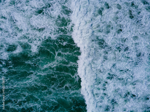 Aerial view high angle view Top-down seawater wave on sandy beach. Aerial view above beach sea in tropical beach sea.