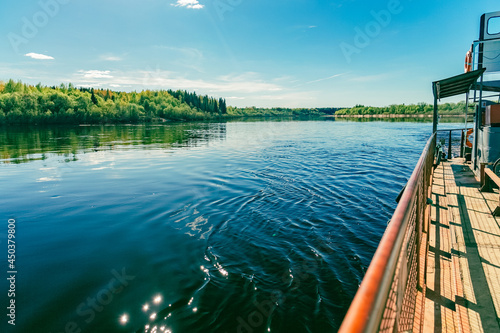 View from the ferry with a view of a summer landscape with a river, a blue sky with clouds, and the shore