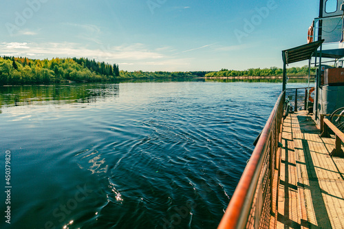View from the ferry with a view of a summer landscape with a river, a blue sky with clouds, and the shore