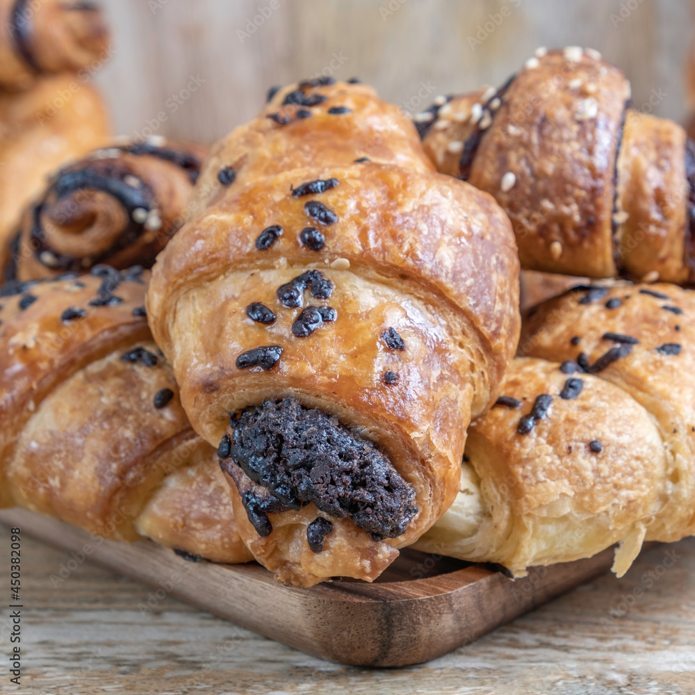Fresh chocolate croissants on wooden background.