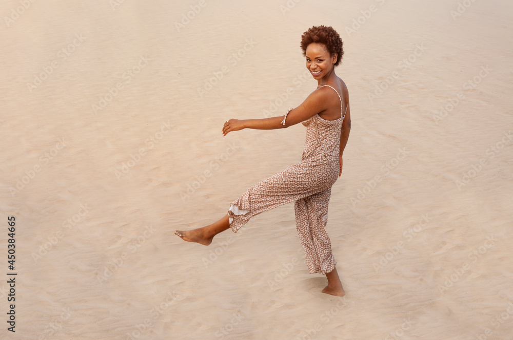 Latin woman happy in the desert sand while looking at camera. Girl with afro, latin people Latin woman happy in the desert sand while looking at camera. Girl with afro, latin people