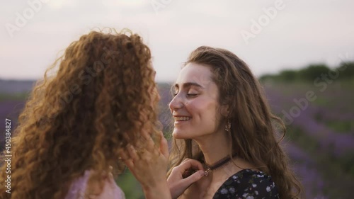 Two sensual women among a lavender field, funny rubbing their noses photo