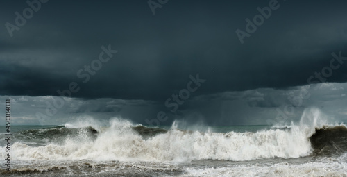 View of a stormy sea and dark cloudy sky, big waves are crashing on the shore