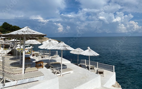 Beach lounge chairs and umbrellas. Beautiful white beach on sea shore at summer day. Sun parasols  loungers against calm water and  blue sky. Wonderful summer. Relaxing holiday on Mediterranean coast.