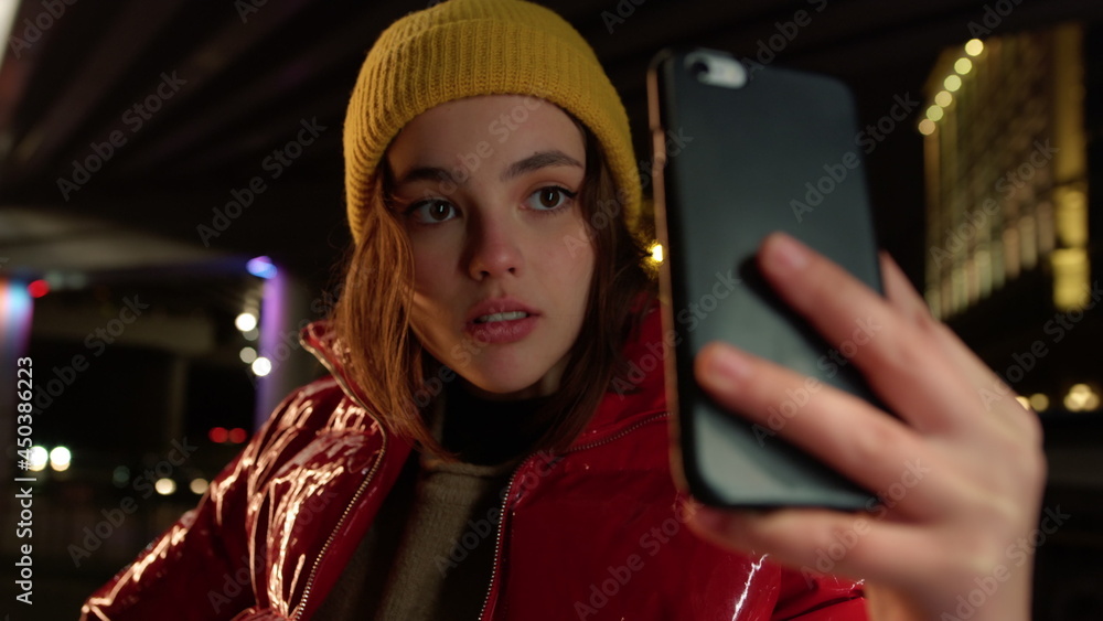 Focused woman taking selfie on smartphone. Girl posing to phone camera outdoor.