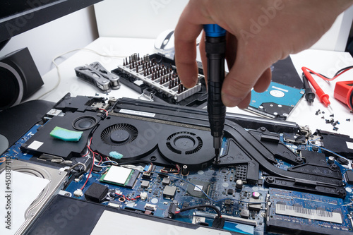 Принти на полотні Laptop repair in a workshop, male hand holds a screwdriver