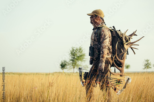 Hunter dressed in camouflage clothing holding a modern bow. photo